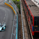 A Formula E car drives alongside a London train